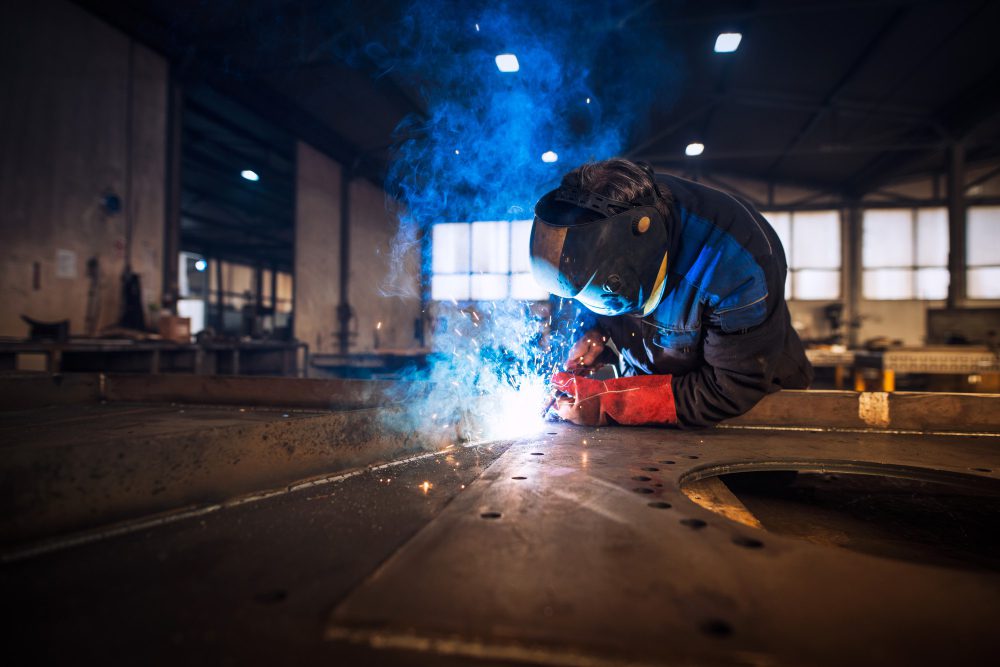 Close up view of worker welding metal construction in industrial workshop<br />